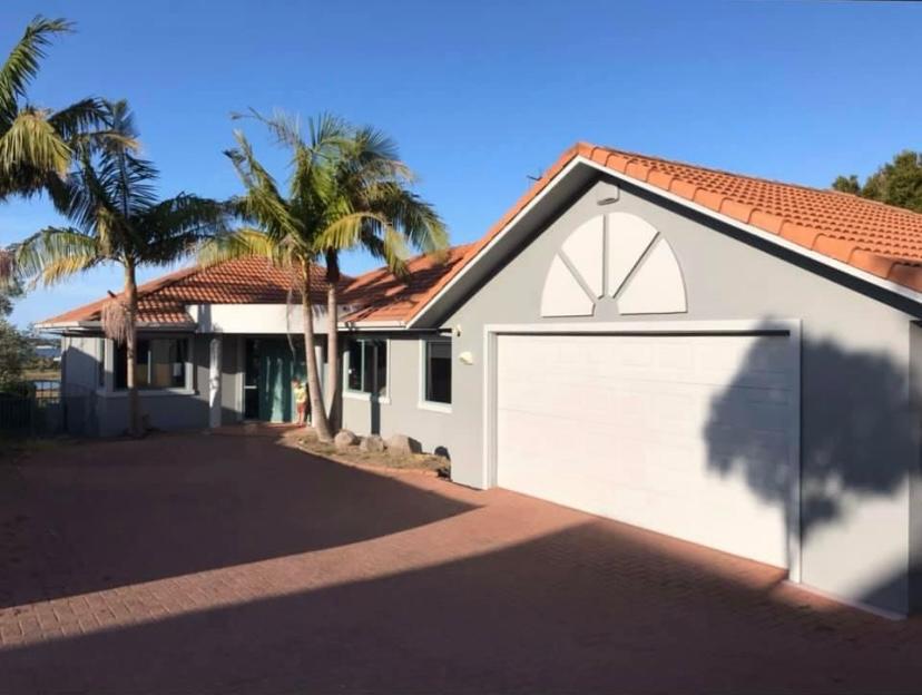 Howick home exterior with pale painted walls, a terracotta roof and paved driveway